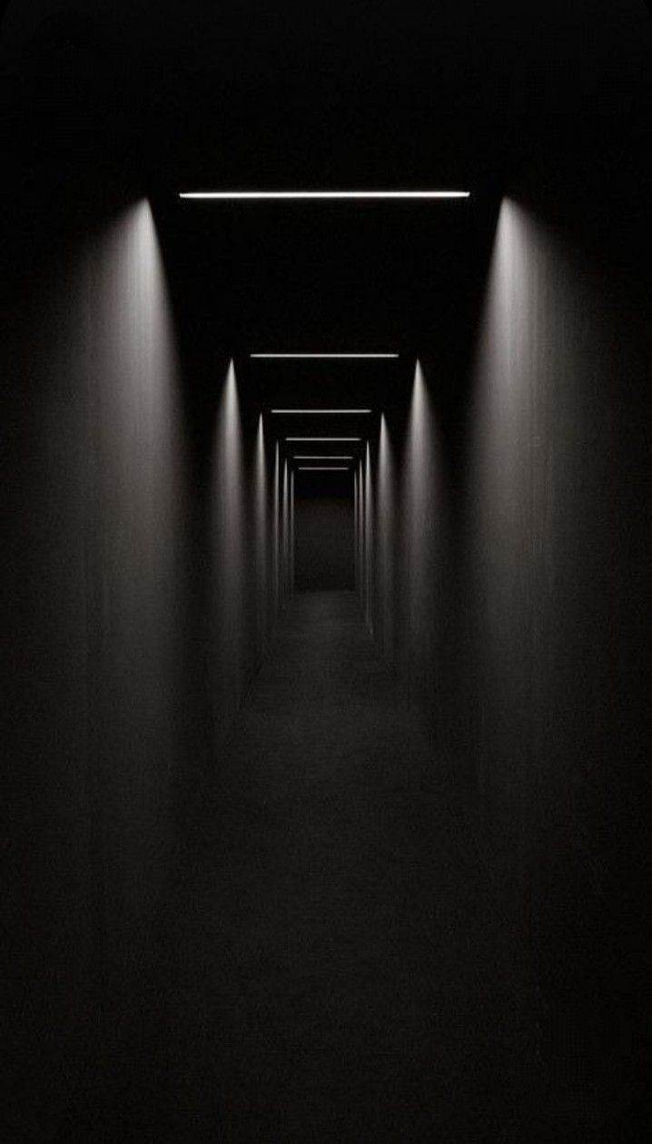 an empty dark hallway with lights on either side and one light at the end in between