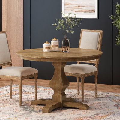 a dining room table with two chairs and a potted plant on the rug in front of it