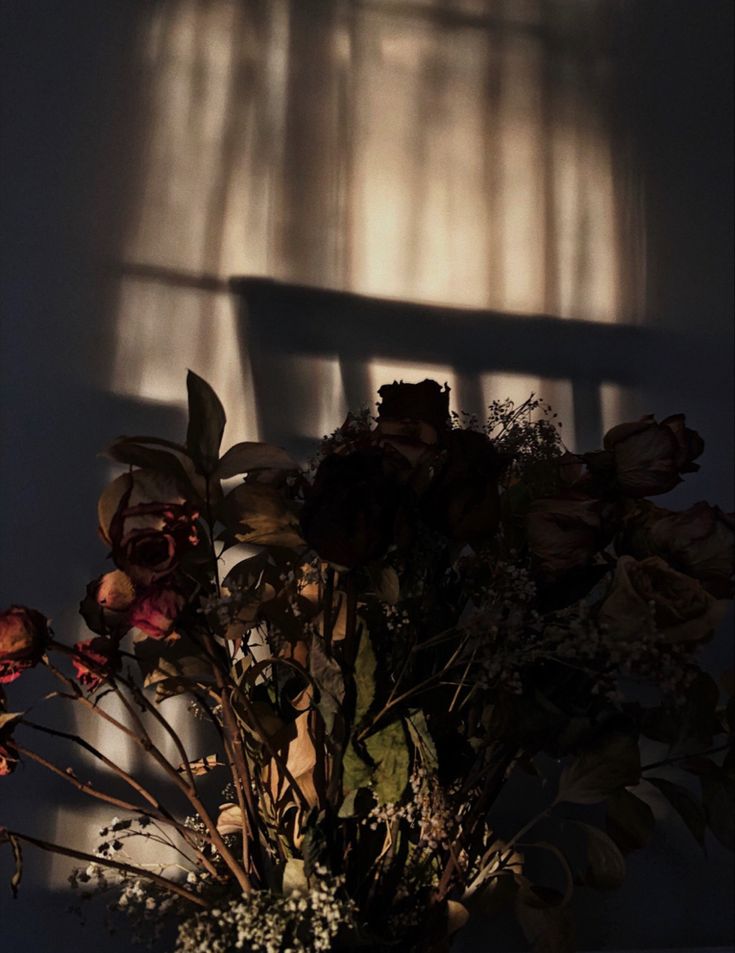 a vase filled with lots of flowers next to a window