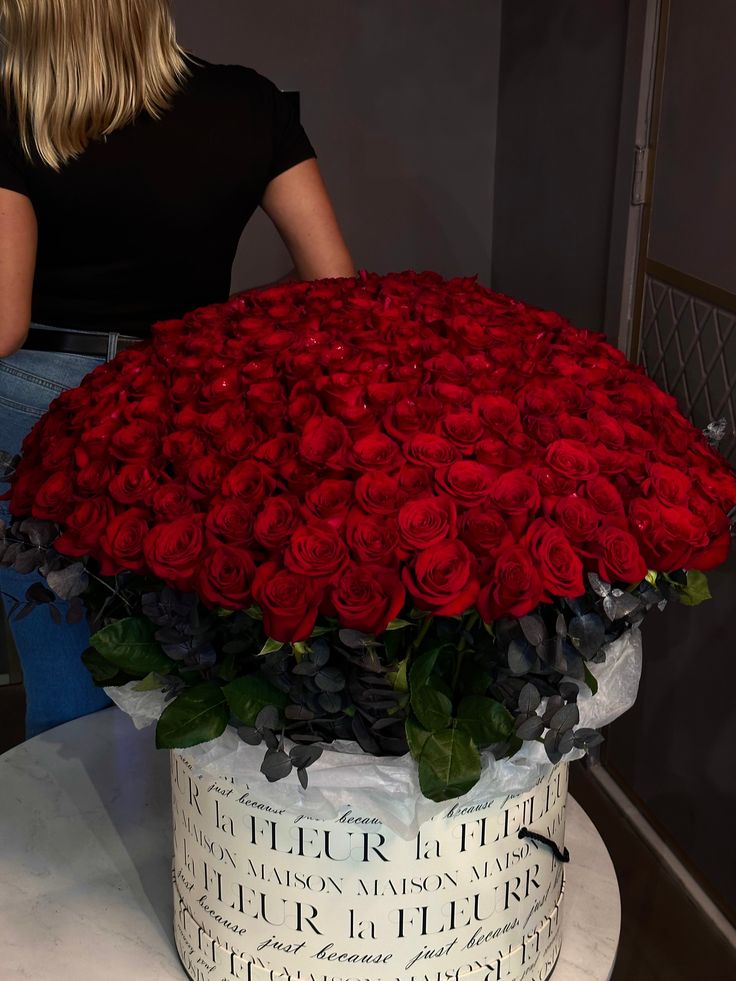 a woman standing next to a large bouquet of red roses