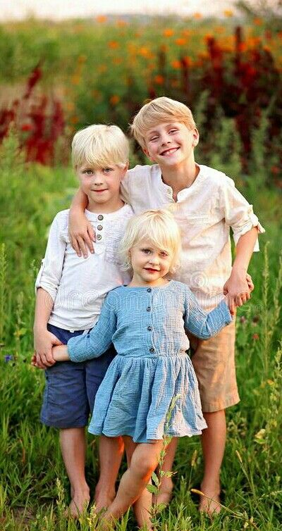 three children are posing for a photo in the grass with their arms around each other