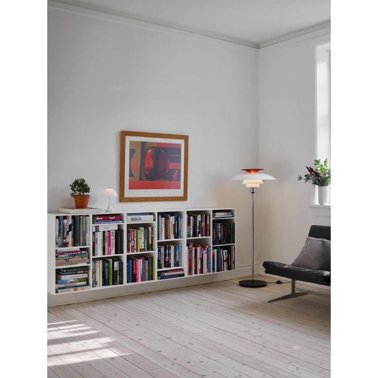 a living room with a book shelf filled with books next to a chair and lamp