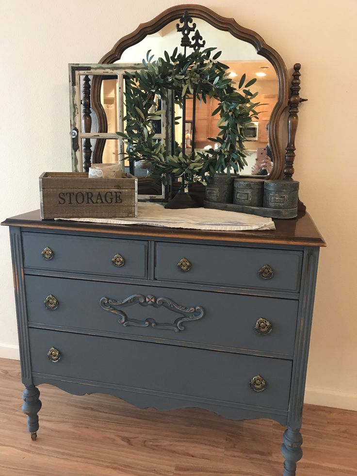 an old dresser with a mirror and wreath on top