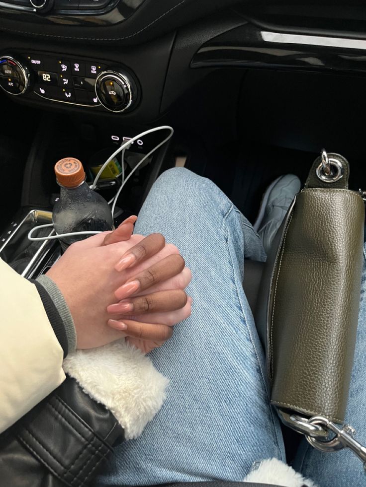 a person sitting in the drivers seat of a car holding their hand on her purse