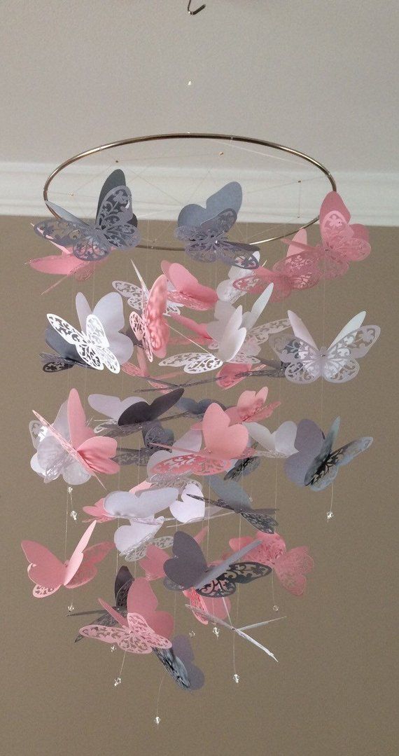 a mobile with pink and blue butterflies hanging from it's side in a room