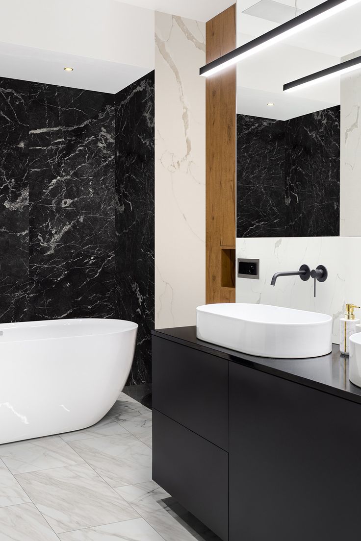 a bathroom with black and white marble walls, flooring and a large bathtub