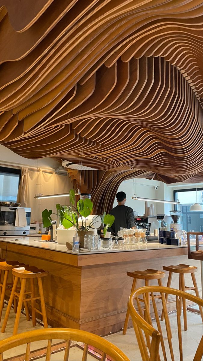 two people sitting at a counter in a room with wooden slats on the ceiling