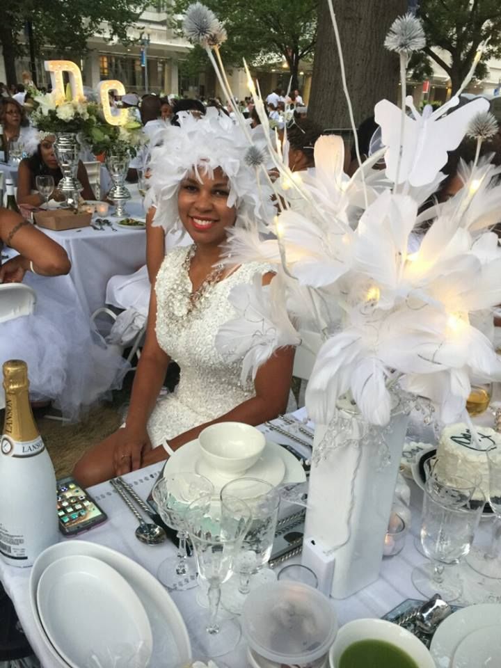 a woman sitting at a table with white plates and silverware