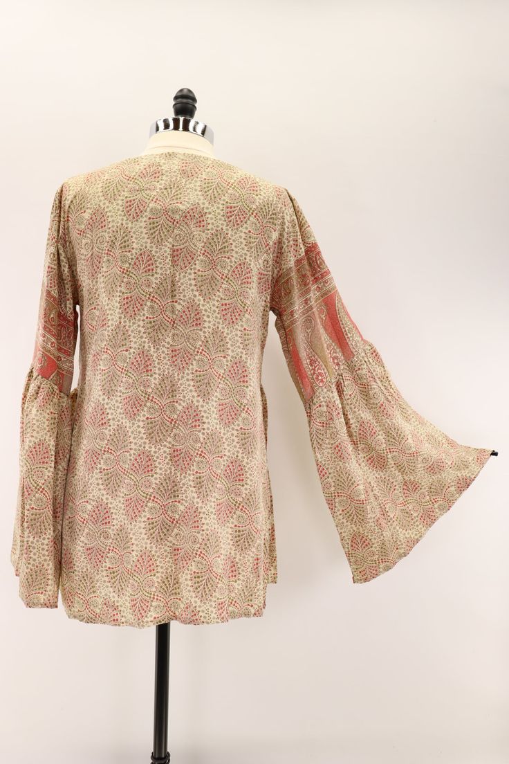 Billowy and romantic, this buttery soft blouse features a v-neckline and bell sleeves. Made from vintage rasgulla silk saris. Available in 3 sizes* S 6-10 M 12-14 L 16-18 Approximately 30” long *Tags were updated with new size designations. Blouse measurements did not change. Some tags will reflect the previous sizing designations. Tag changes are as follows… S/M to S L/XL to M XXL to L Care Instructions: Hand wash and line dry for longest life. Disclaimer: The material used in this style is rep Bohemian V-neck Rayon Peasant Top, Bohemian V-neck Blouse With Boho Print, Festive V-neck Kurta With Block Print, Flowy V-neck Rayon Peasant Top, Silk Blouse With Blouson Sleeves And V-neck, Bohemian Long Sleeve Tops With Gathered Sleeves, Long Sleeve Bohemian Cream Blouse, Bohemian V-neck Blouse With Gathered Sleeves, Bohemian Blouse With Gathered Sleeves, V-neck