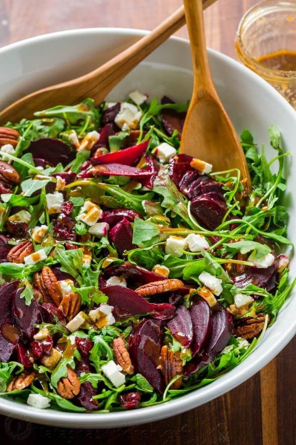 a salad with beets, pecans and feta cheese in a white bowl