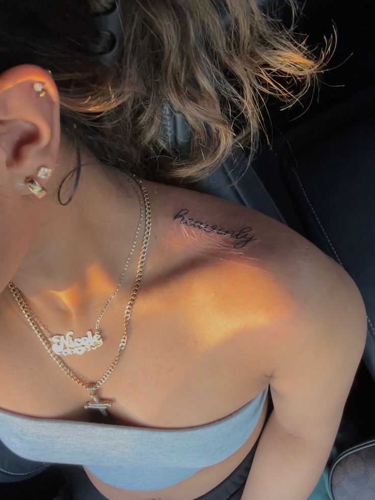 a woman with tattoos on her chest sitting in the back seat of a car wearing a necklace and earring