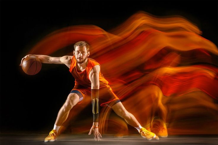 a man holding a basketball in front of an orange and red background with the ball