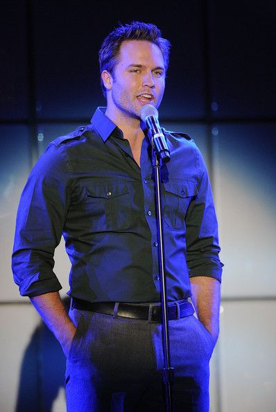 a man standing in front of a microphone with his hands on his hips and looking at the camera