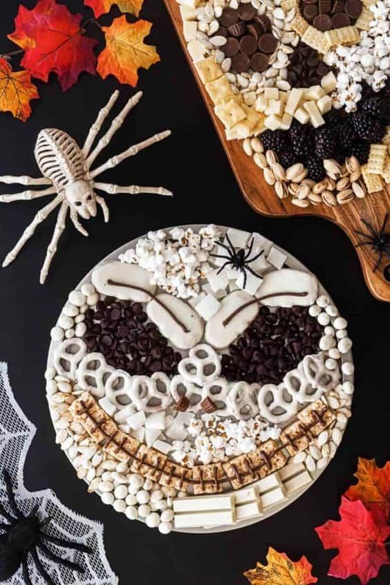 a cake decorated with white frosting, chocolate chips and sprinkles in the shape of a face