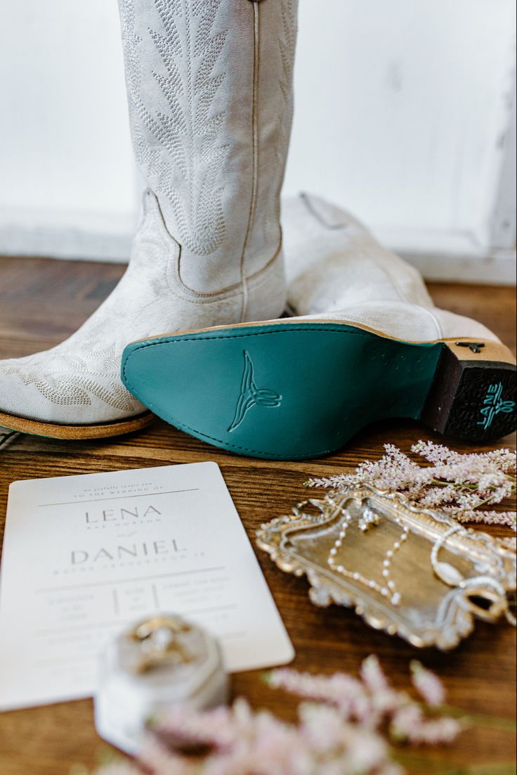 the boots are sitting on the table next to the wedding ring and other items that have been placed around them