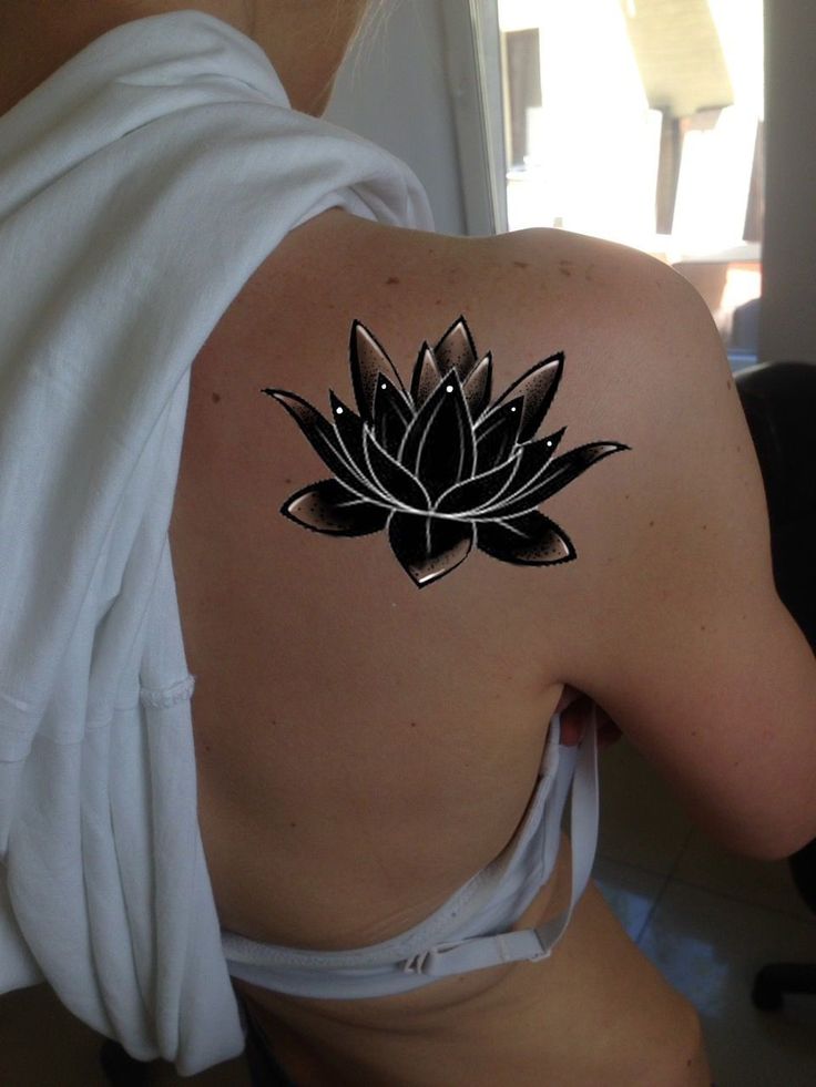 a woman with a tattoo on her back has a lotus flower tattooed on her shoulder