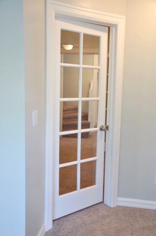 an empty room with a white door and carpeted floor in front of the doorway