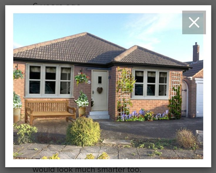 a brick house with a bench in front of it and flowers growing on the windows