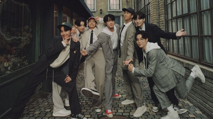 a group of young men standing next to each other on a brick road in front of tall buildings