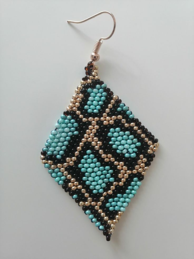 a pair of beaded earrings hanging from hooks on a white surface, with beads in the shape of squares and rectangles