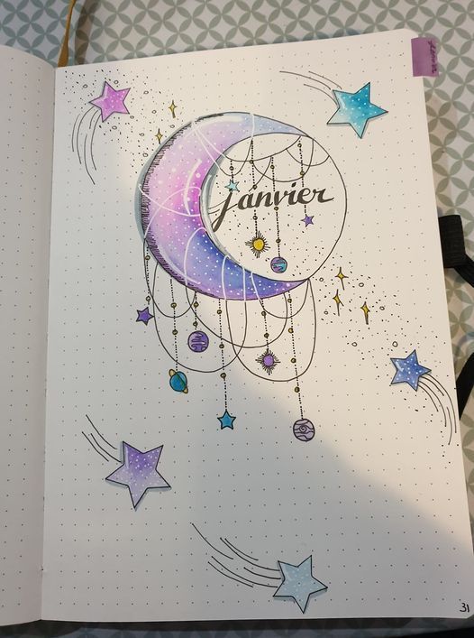 an open notebook with a drawing of a moon and stars on the cover, which reads janner