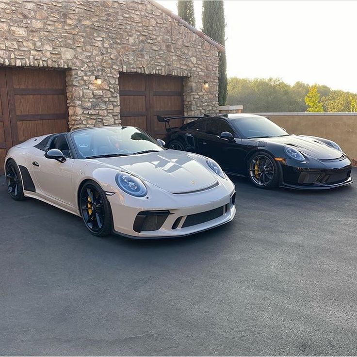 two sports cars parked in front of a garage