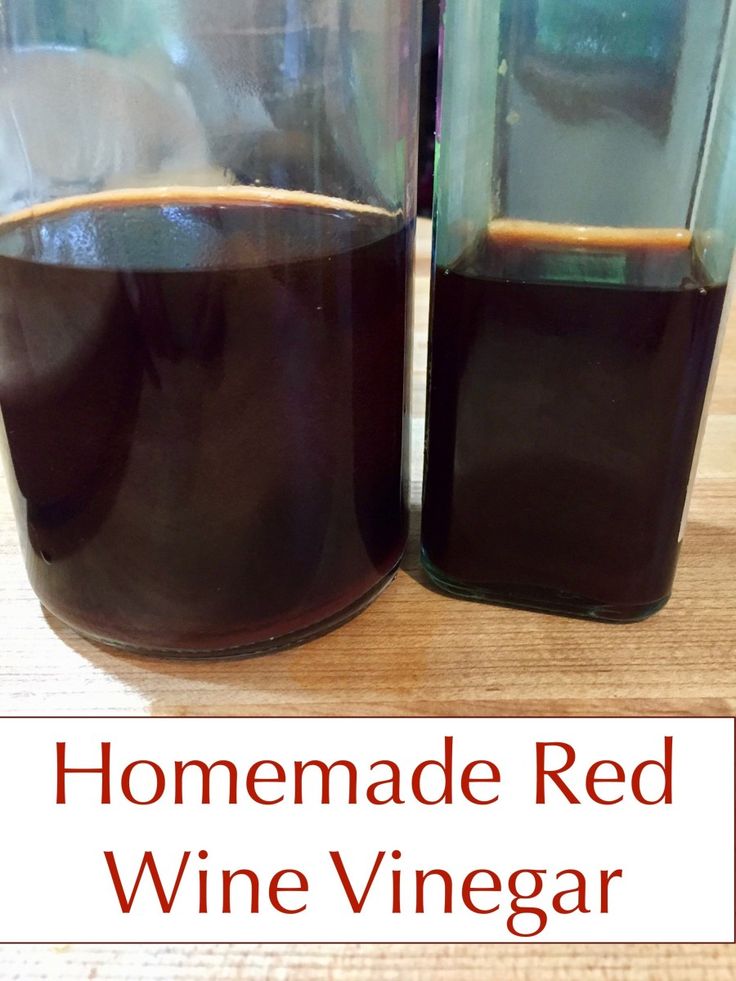 homemade red wine vinegar in two glass containers on a wooden table with text overlay that reads homemade red wine vinegar