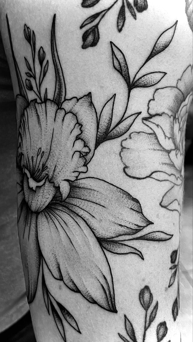 a woman's thigh with flowers and leaves tattoo on her leg, in black and white