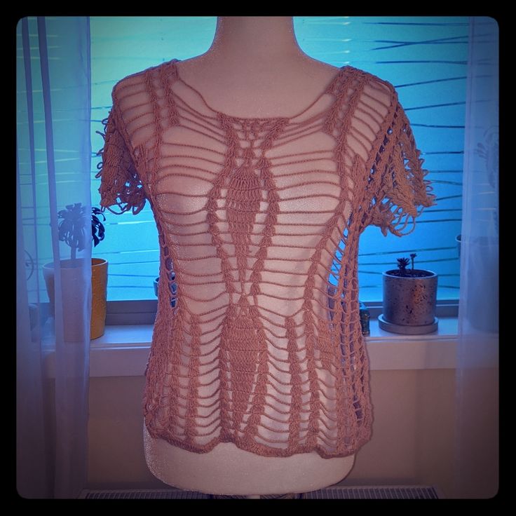 a crocheted top is displayed on a mannequin's dummy in front of a window