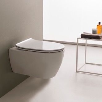 a white toilet sitting in a bathroom next to a wall mounted shelf with towels on it