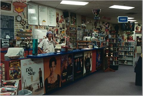 a man is standing at the front desk of a book store with posters on the wall