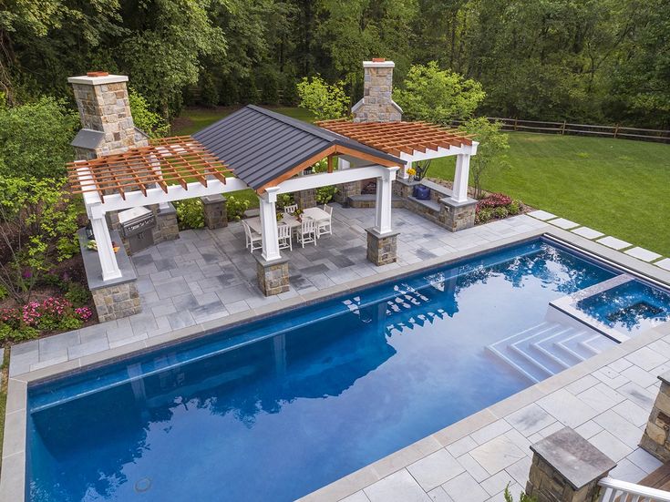 an aerial view of a swimming pool and patio with pergolated roof, seating area, and outdoor kitchen