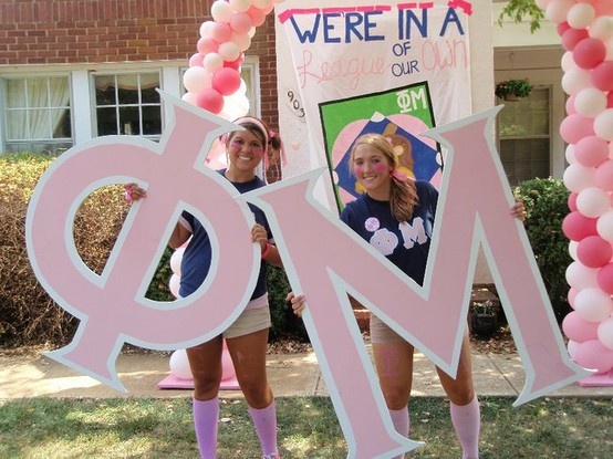 two girls are standing in front of a sign that says omi and there is a balloon arch