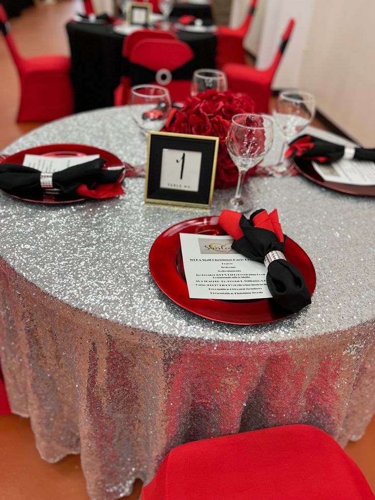 the table is set with silver sequins and red plates