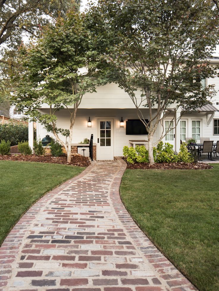 a brick walkway leading to a white house