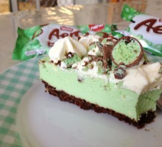 a piece of cake on a plate with a spoon and candy bar in the background