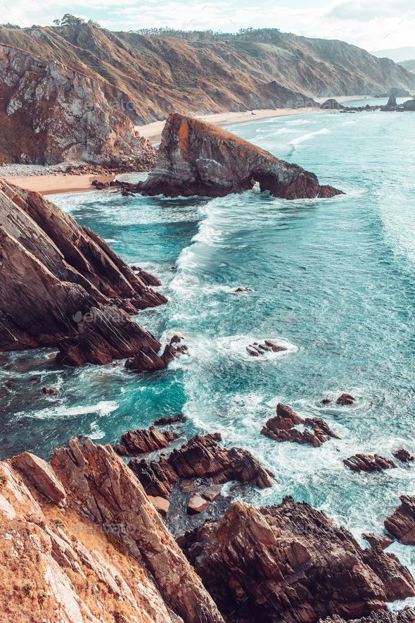 an aerial view of the ocean and rocky coastline