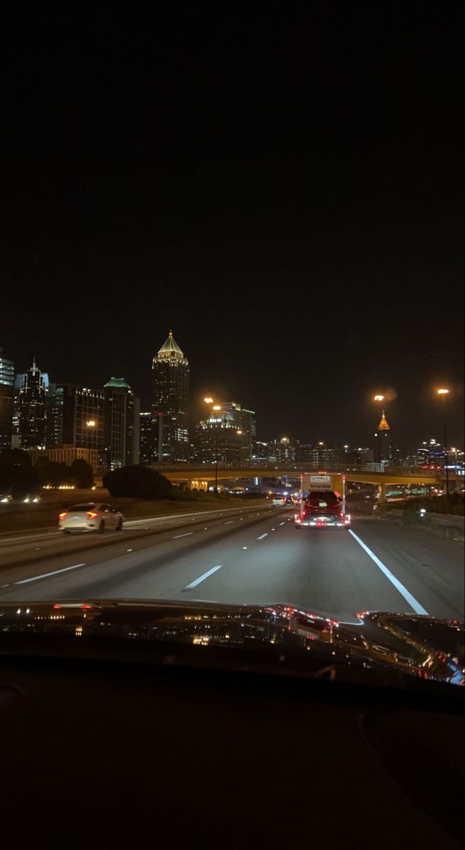 the city lights shine brightly in the night sky over an interstate highway with cars driving on it