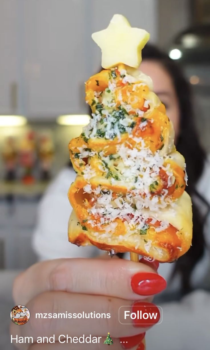 a woman holding up a piece of food with cheese and spinach on it in front of her face