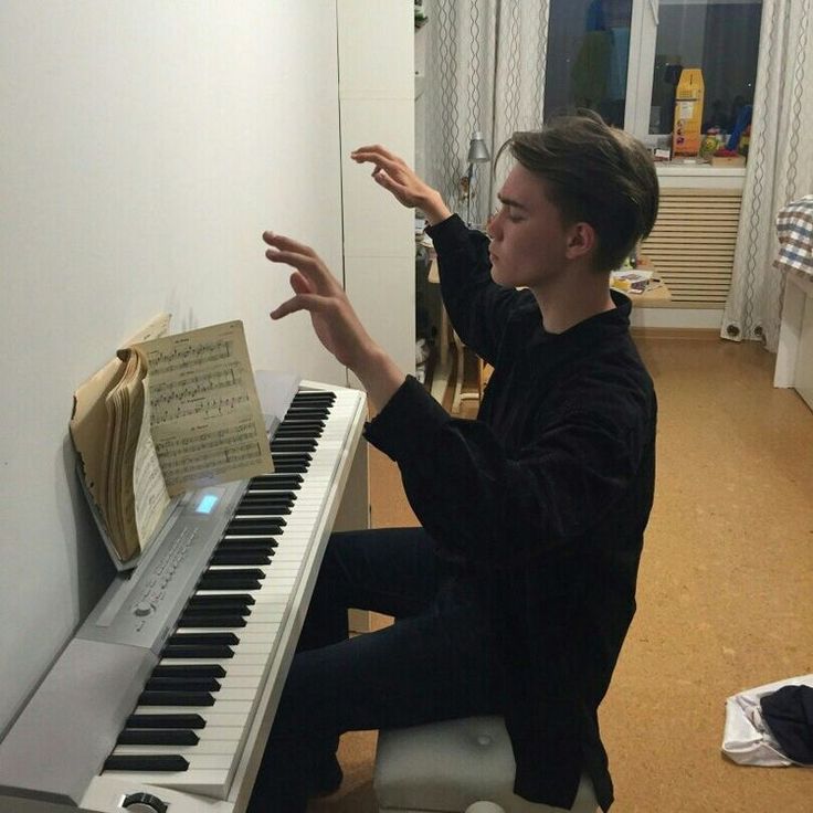 a young man sitting at a piano playing music