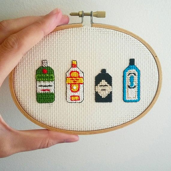 a hand is holding up a cross stitch embroidery kit with four different bottles on it