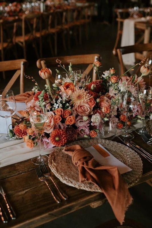 an arrangement of flowers and wine glasses on a table at a wedding reception with place settings