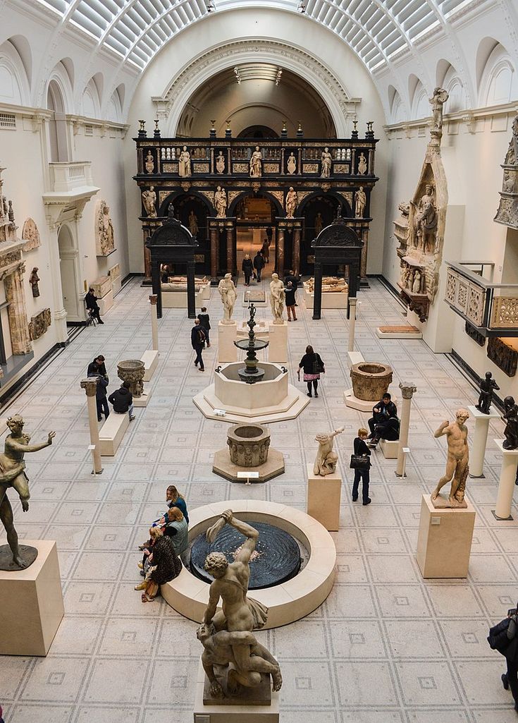 people are looking at statues in the middle of a room with white walls and ceilings