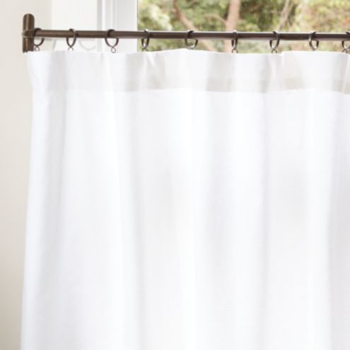 a white curtain hanging in front of a window with a tree outside the window behind it