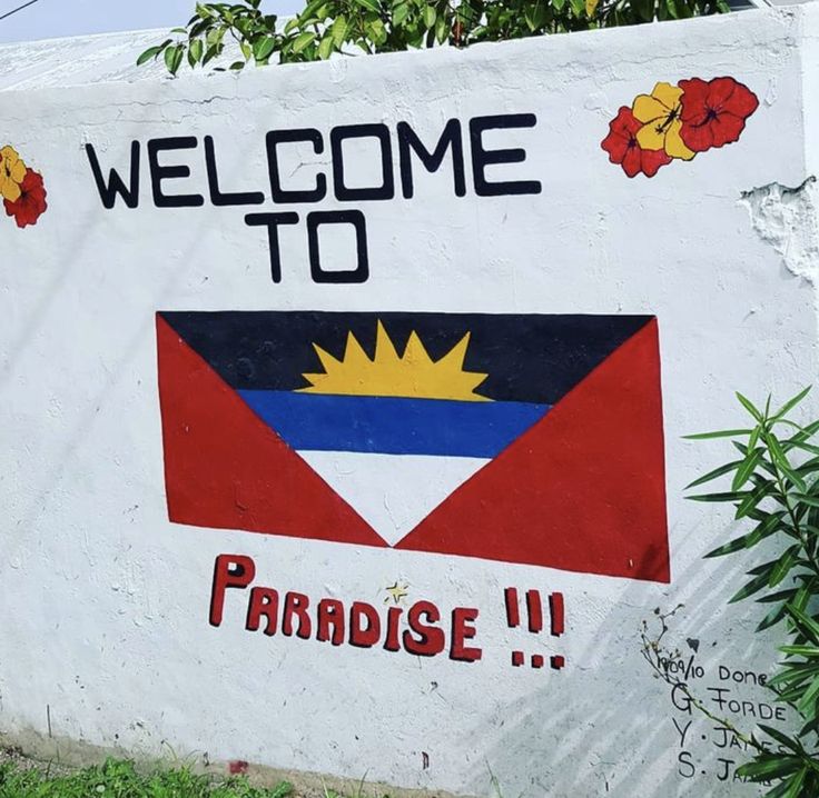 a welcome to paradise sign painted on the side of a white wall with red, blue and yellow designs