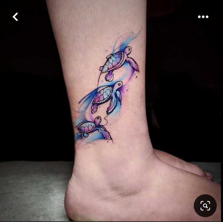 a small tattoo on the foot of a woman's leg with two turtles in blue watercolors