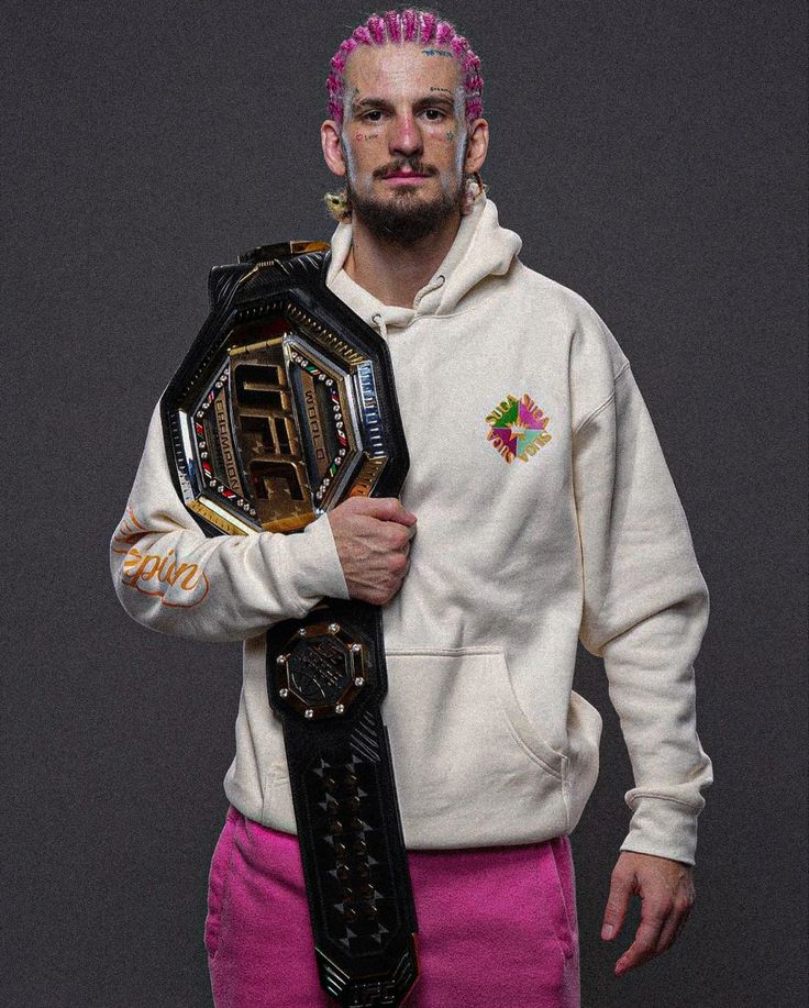 a man with pink hair holding a wrestling belt