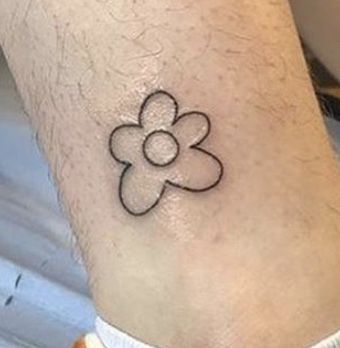 a person with a small tattoo on their foot that has a flower in the middle