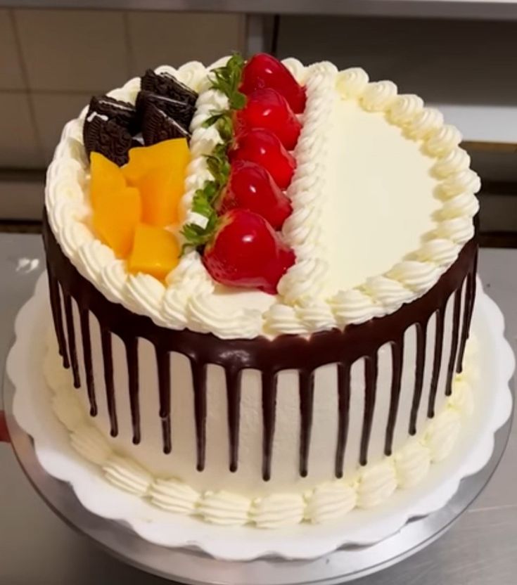 a white cake with chocolate icing and fruit on top