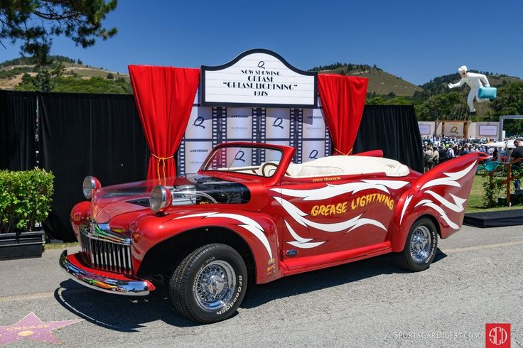 an old fashioned red car parked in front of a sign